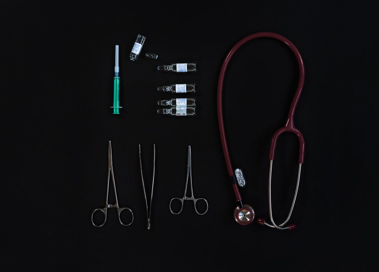 Flat lay of medical equipment including stethoscope, syringe, and tools.